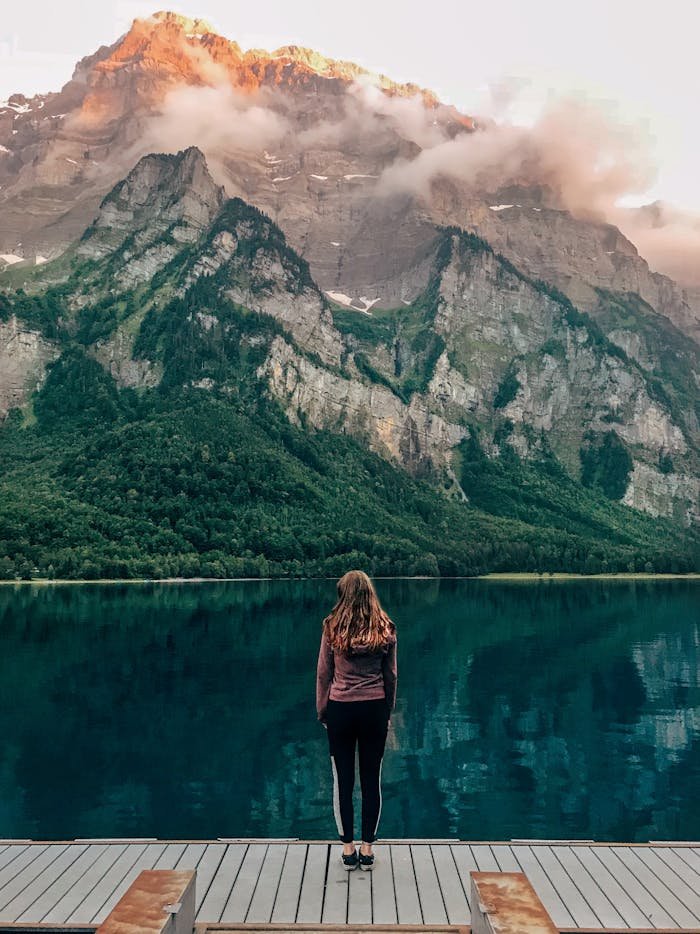 Woman standing at Klöntalersee in Switzerland with scenic mountain background.