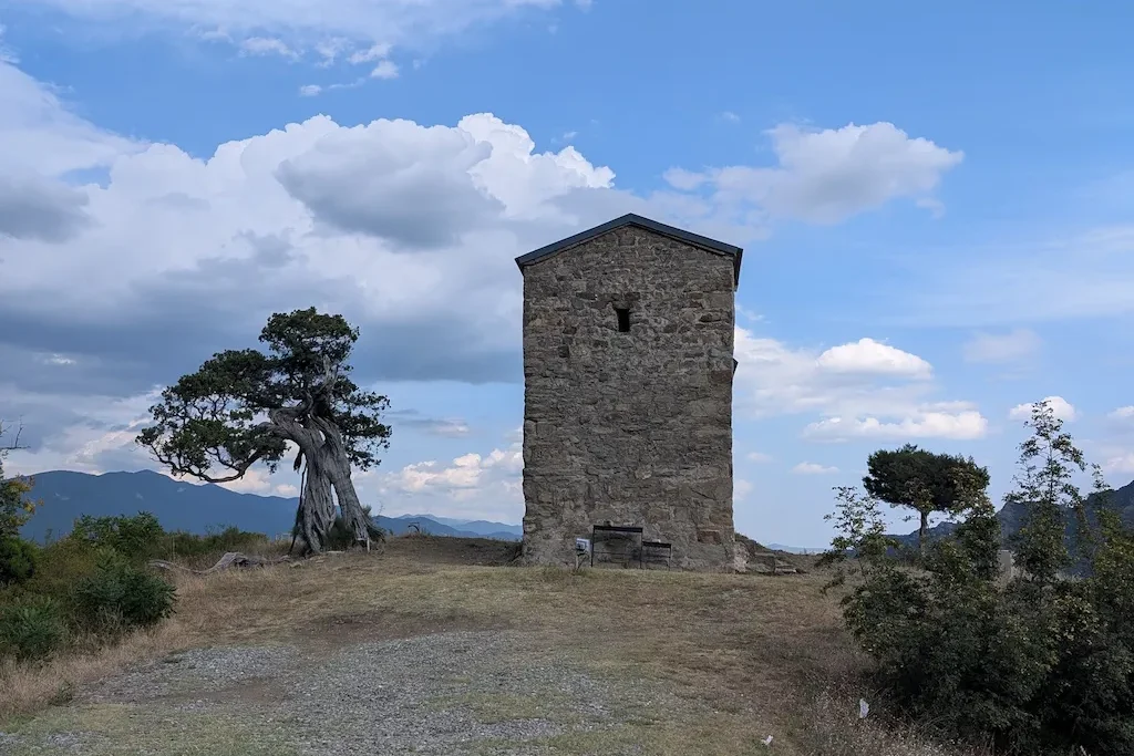 Kaloubani St George Church and a large juniper tree against the mountain landscape