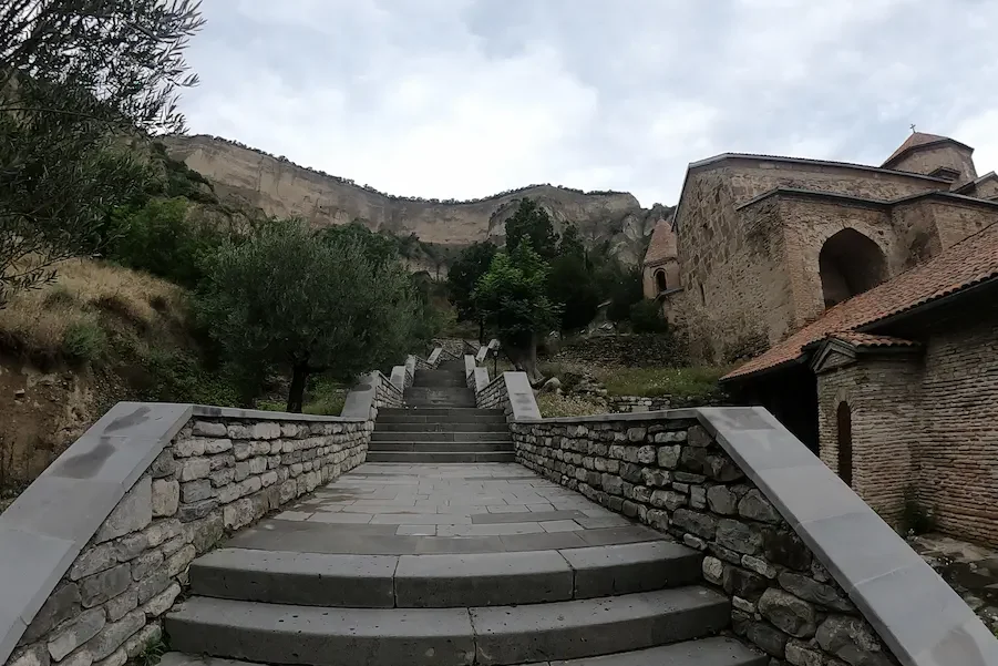 Stone steps and monastery buildings beneath the limestone cliffs at Shio Mghvime
